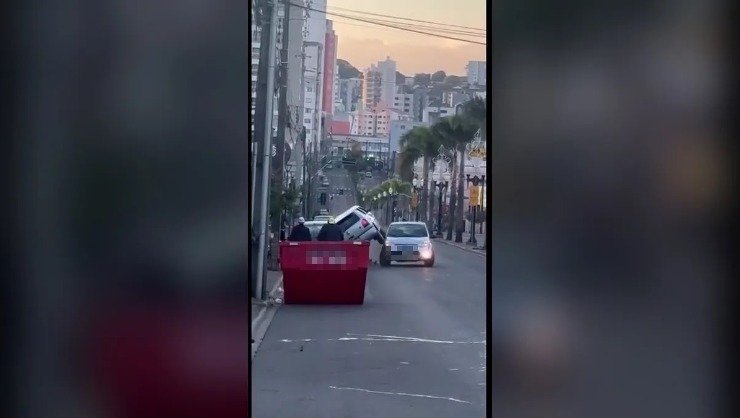 Carro inclinado sobre outro ao lado de caçamba na Avenida Tupi